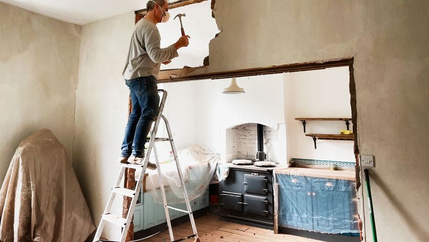 man on ladder knocking down a wall between the dining room and kitchen
