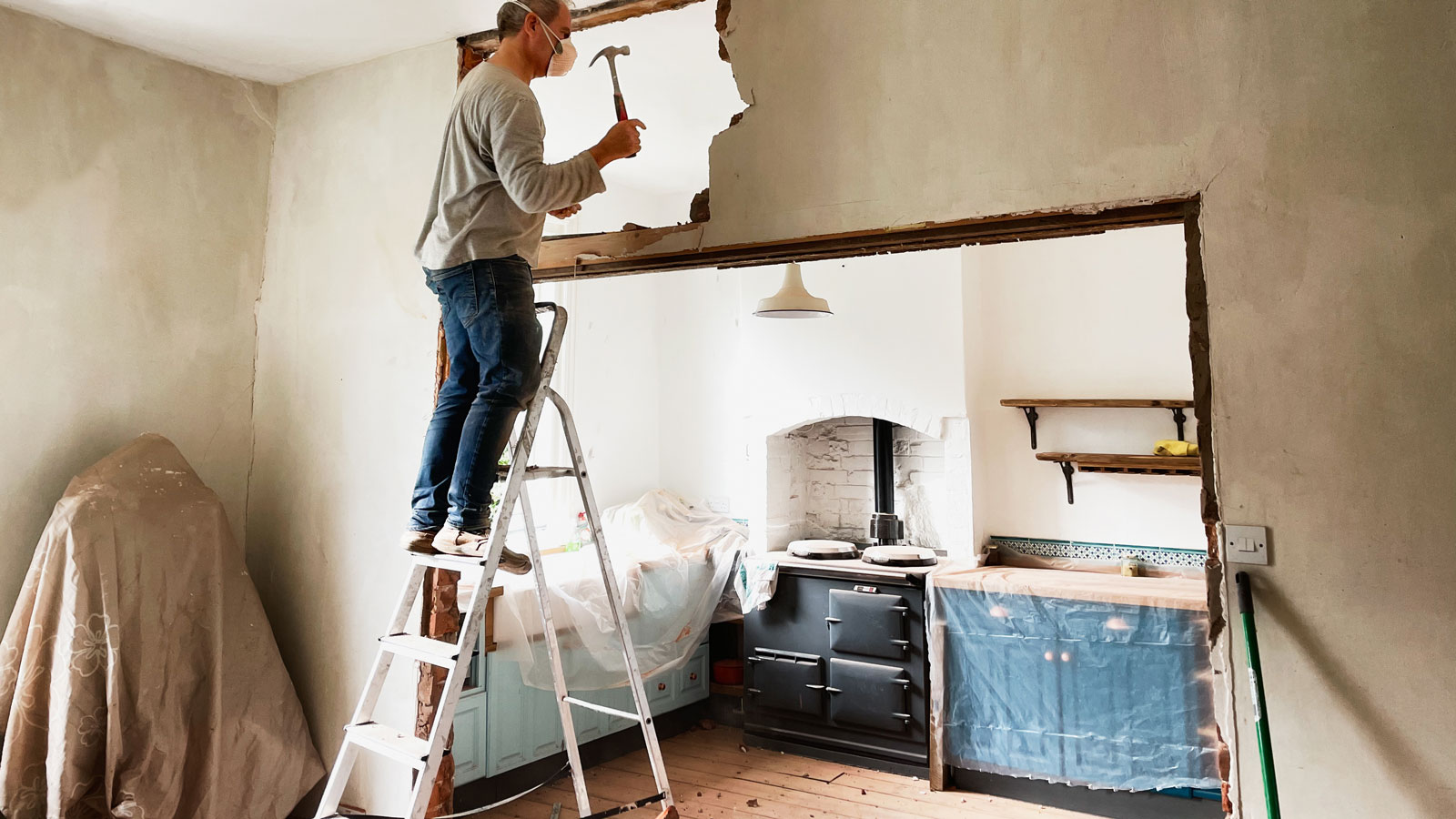 man on ladder knocking down a wall between the dining room and kitchen