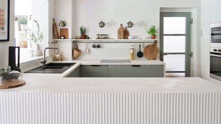 Fluted panel in modern off-white and sage green kitchen with black hardware and microcemented counters