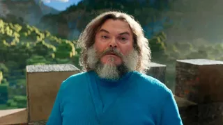 jack black wears a blue shirt in the minecraft world with blocks behind him in a still from the minecraft movie