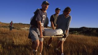 Researchers David Krause (left front) and team carry a plaster jacket containing the skeleton of the early mammal now called Adalatherium hui.