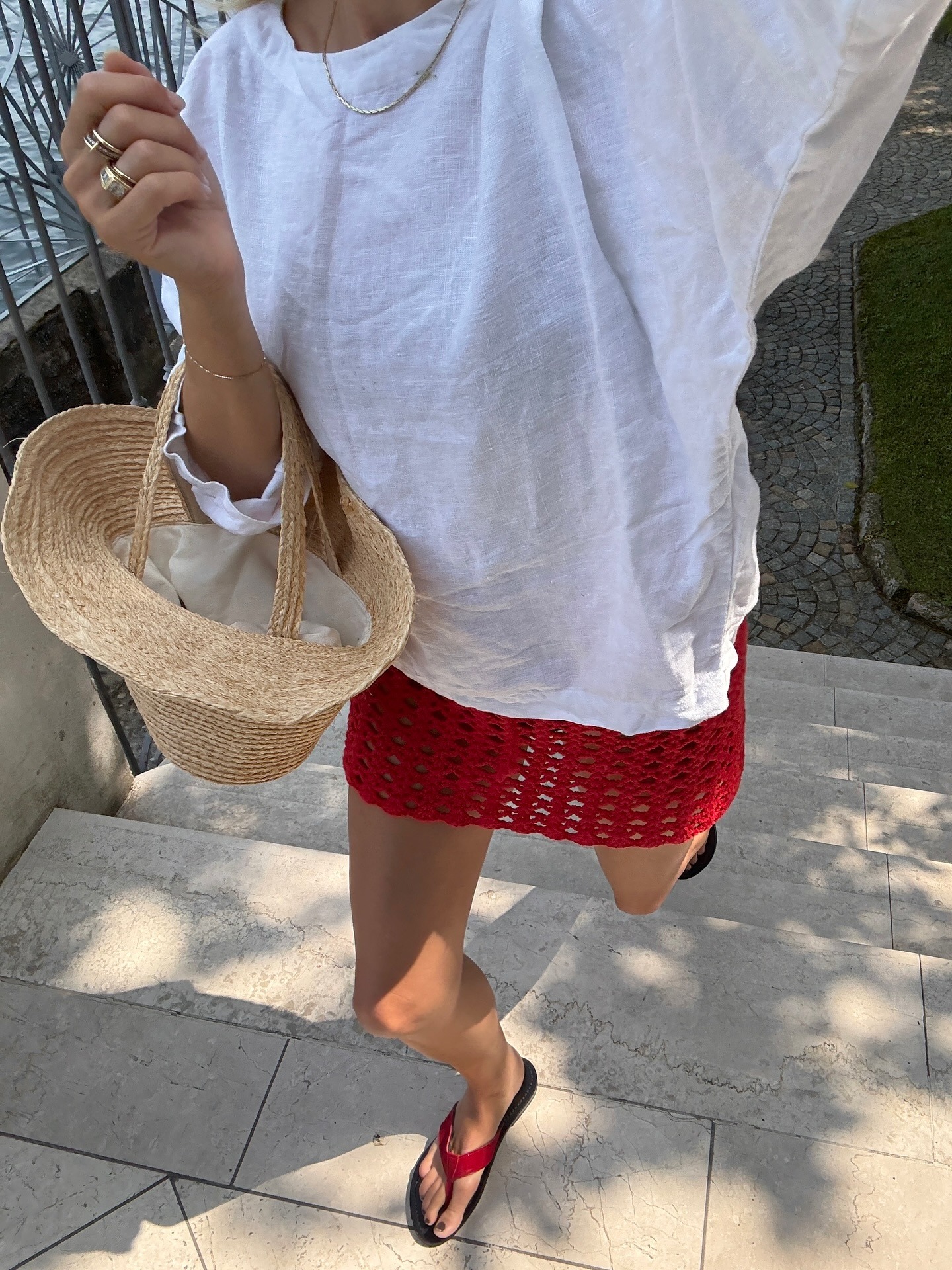 Woman in white tee, red skirt, and red flip-flops