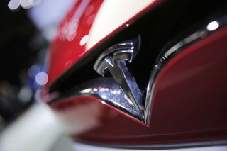 The Tesla &#039;T&#039; symbol seen on the front of a red Model X