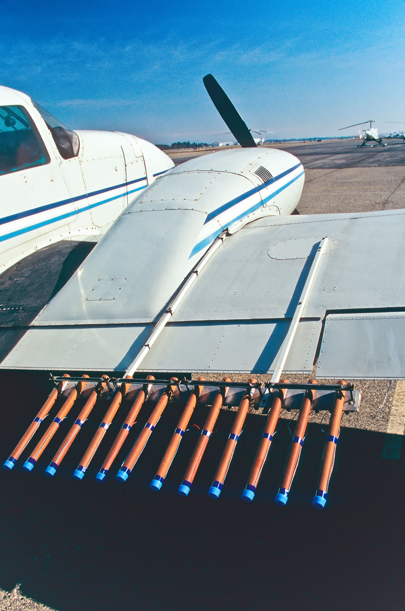 A view of a white plane wing with various orange and blue flares attached to the back