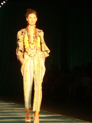 Model wearing a layered outfit with long strings of coloured beads