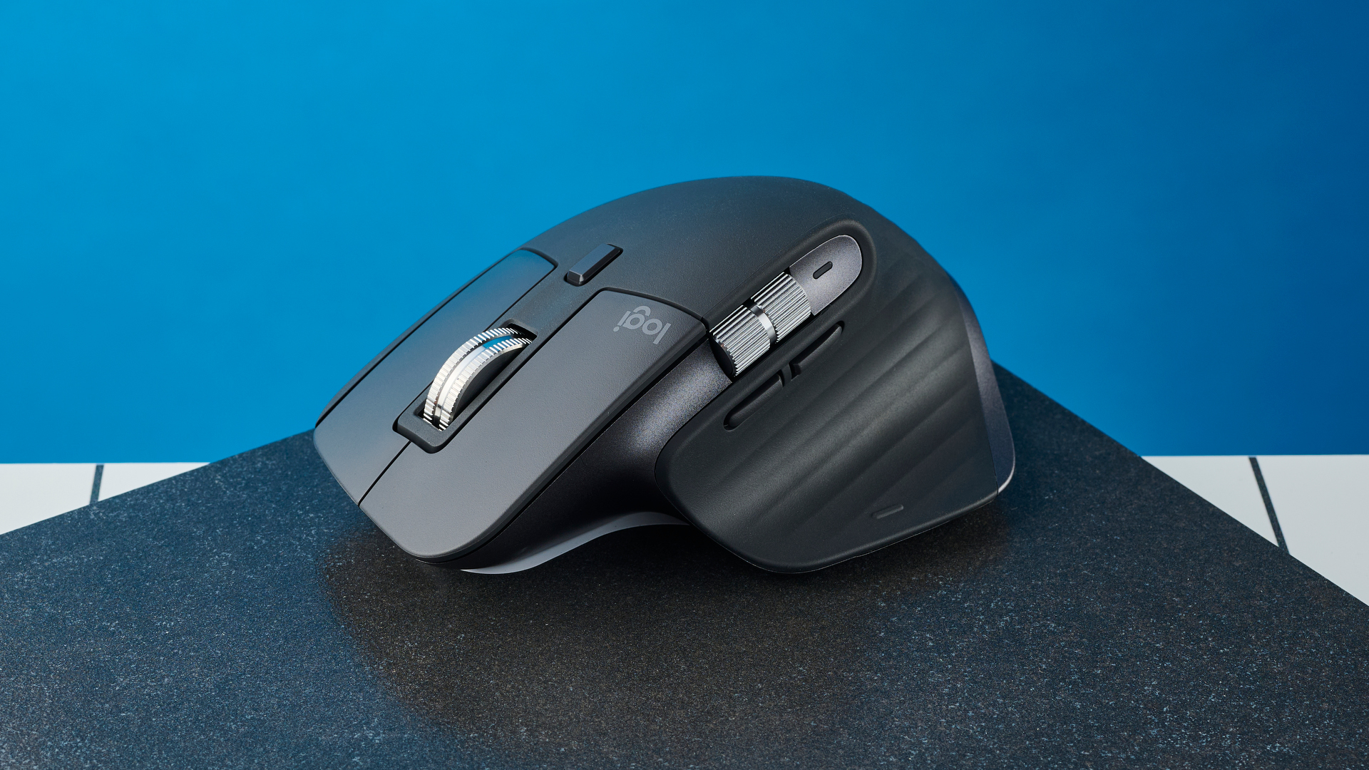 A photo of the Logitech MX Master 3S on a black board against a blue background.