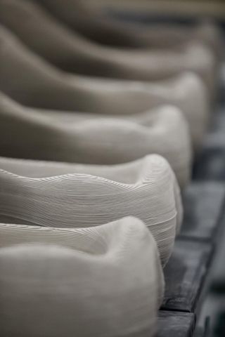 A detail shot showing the ridged surface of the 3D printed white ceramic on a series of basins shown on a line