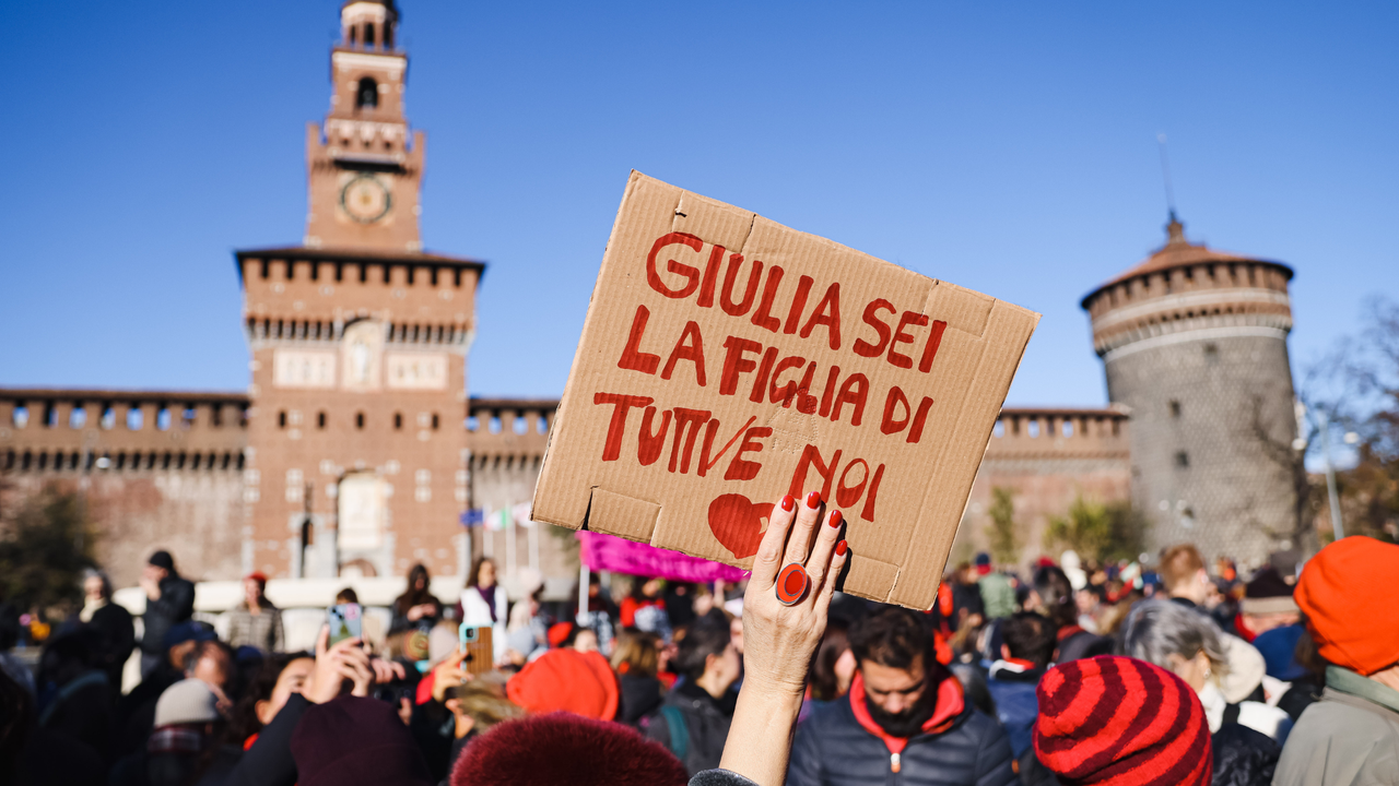 A sign that reads, in Italian, 'Giulia you are the daughter of all of us' in front of a crowd protesting in Italy