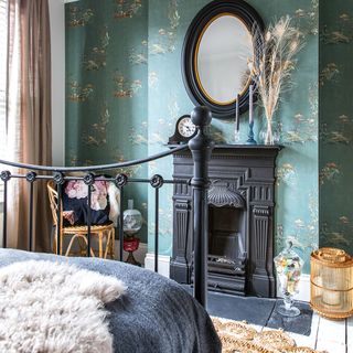 bedroom with green wallpaper and black cast iron fireplace