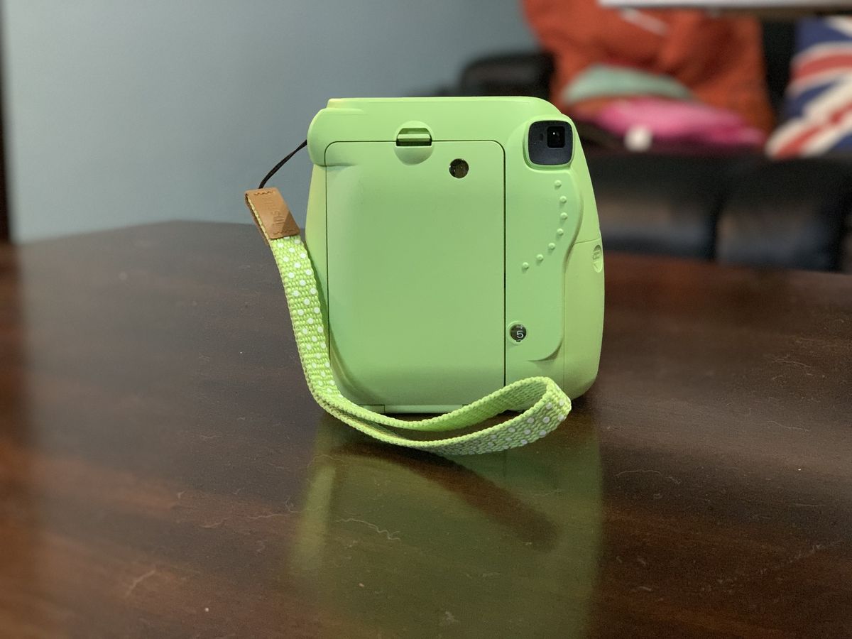 Green Fujifilm Instax Mini 9 on wood table back view