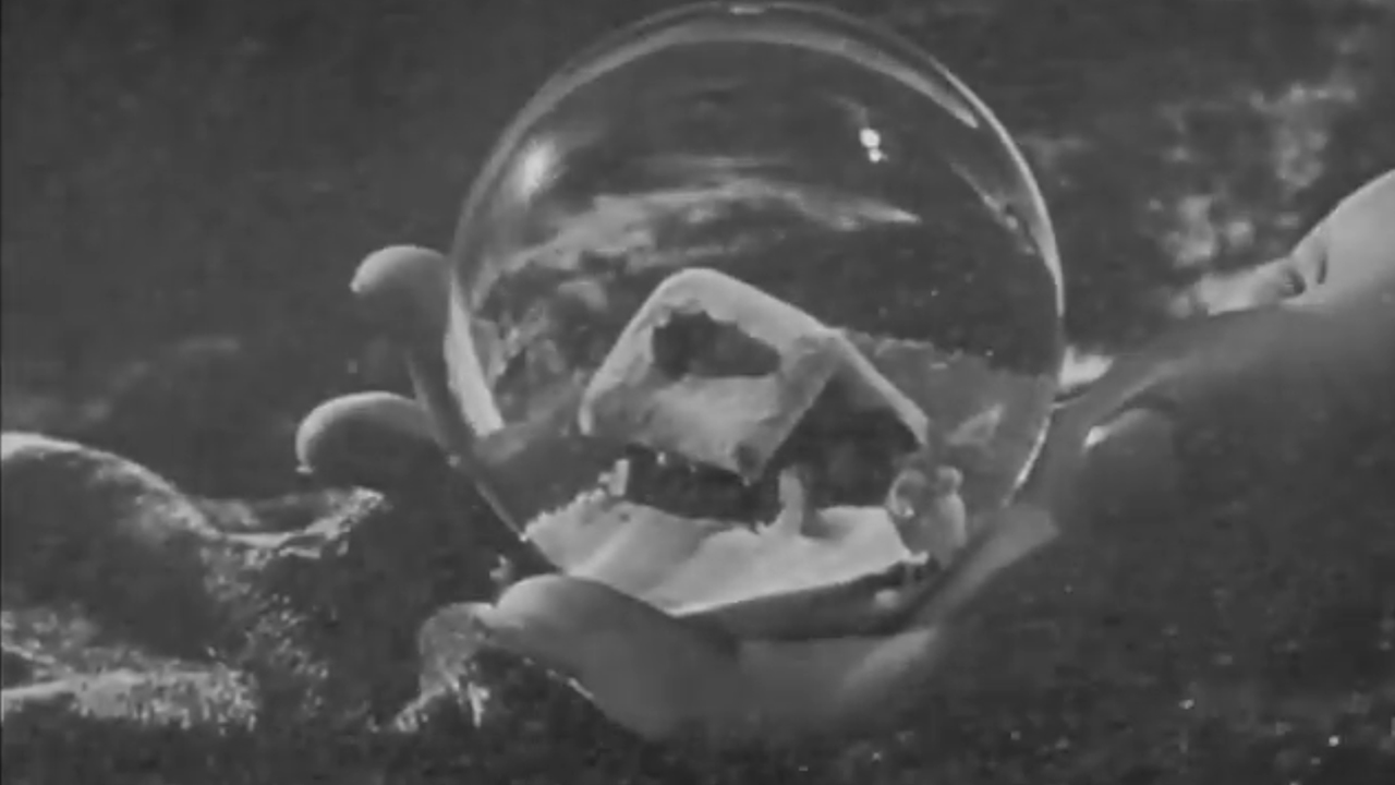 A close up of a hand holding a snow globe in the opening scene of Citizen Kane