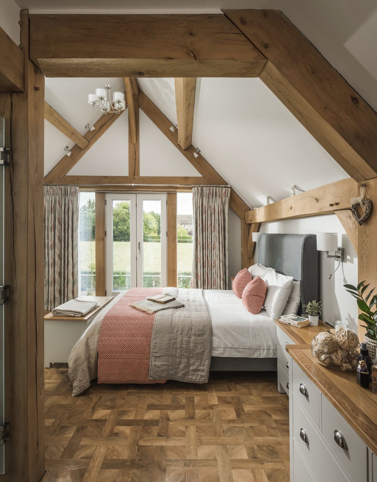 bedroom in an oak frame home with parquet floors and french doors leading out to a garden