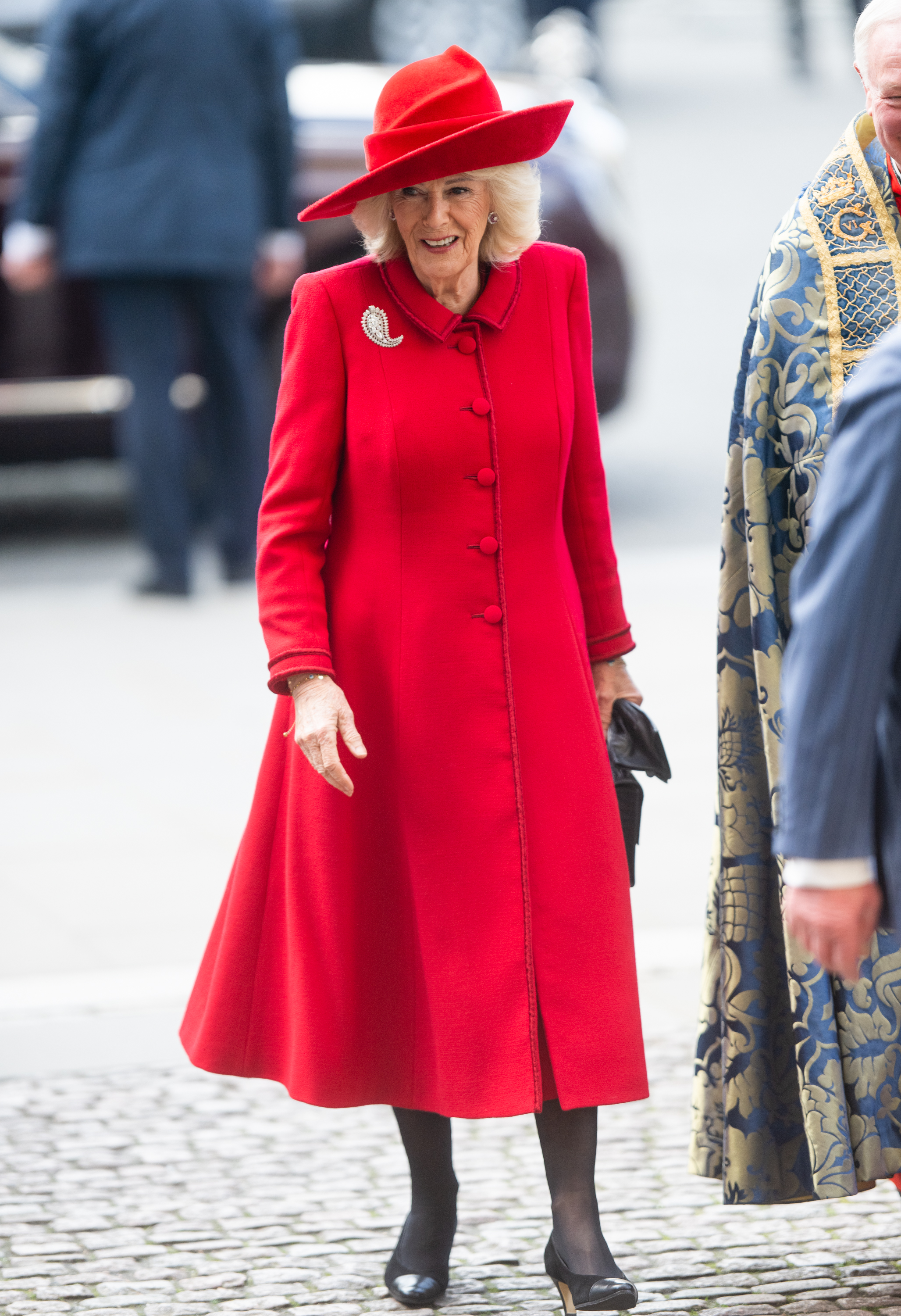 Queen Camilla wearing a red coat and hat smiling