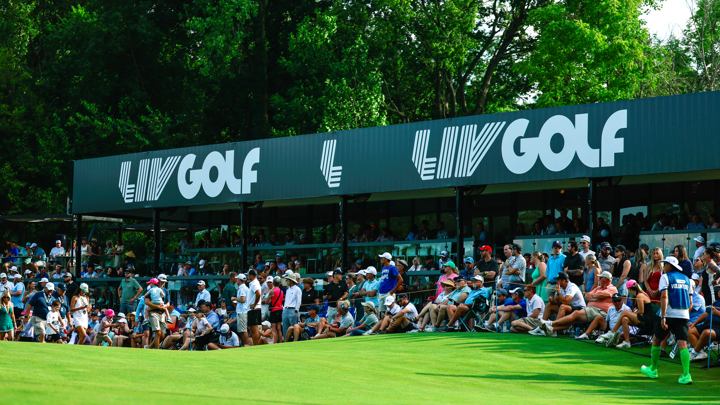 A general view of fans at a LIV Golf event with a large horizontal LIV Golf sign in the background