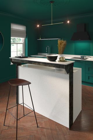 A kitchen painted with green wall paint decor and white kitchen island with bar style seating