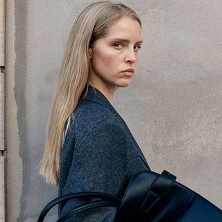 An H&amp;M model carrying a black open-top shopper tote.