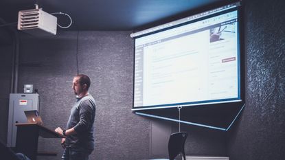 Man teaching in front of projector screen