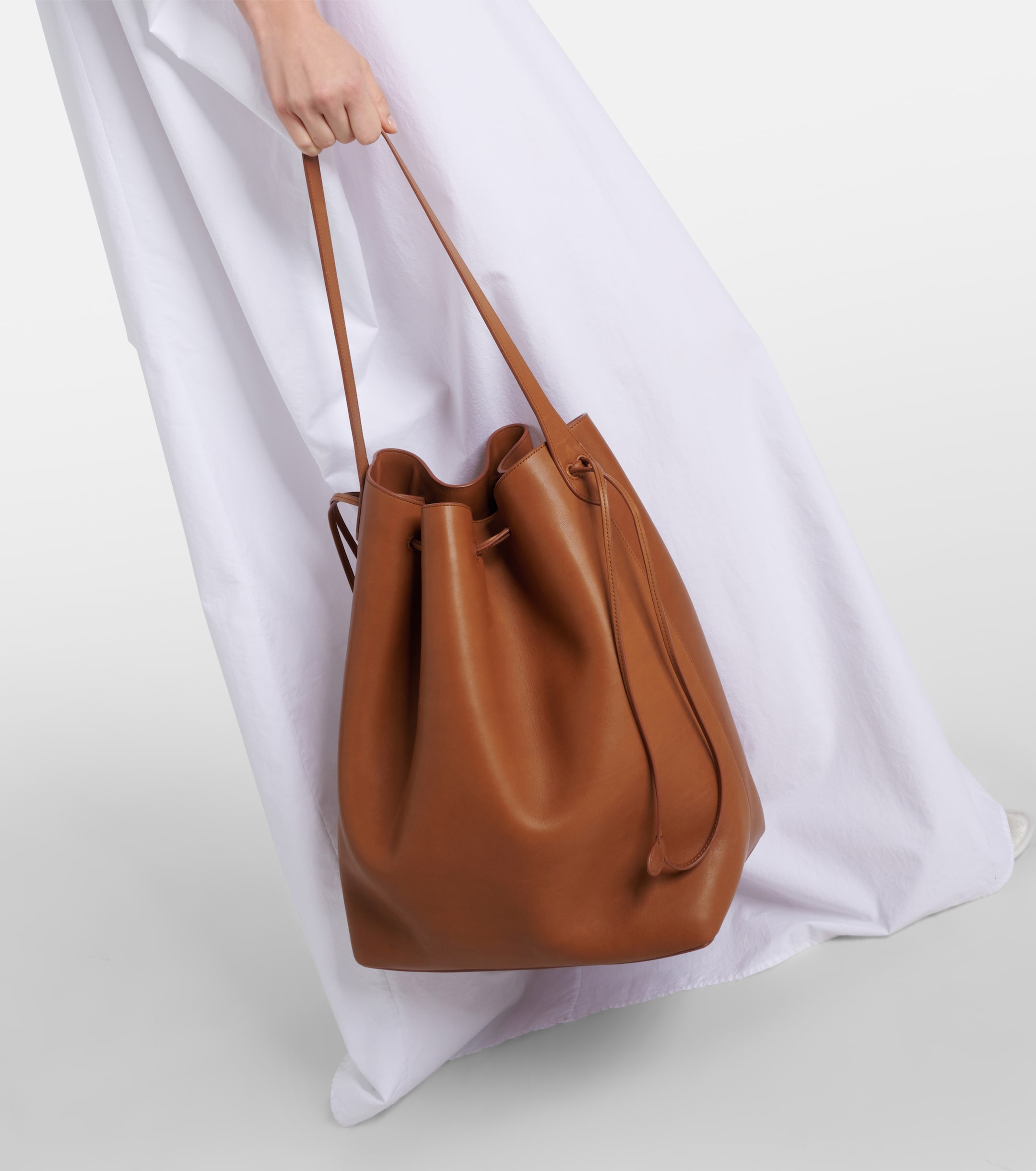 a model carrying a brown leather bucket bag from the row