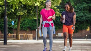 Two women laughing and smiling, walking together for exercise