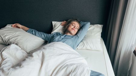 A woman lies in bed happily asleep.