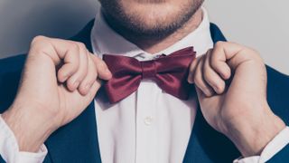 A man tightening a red bow tie on his shirt