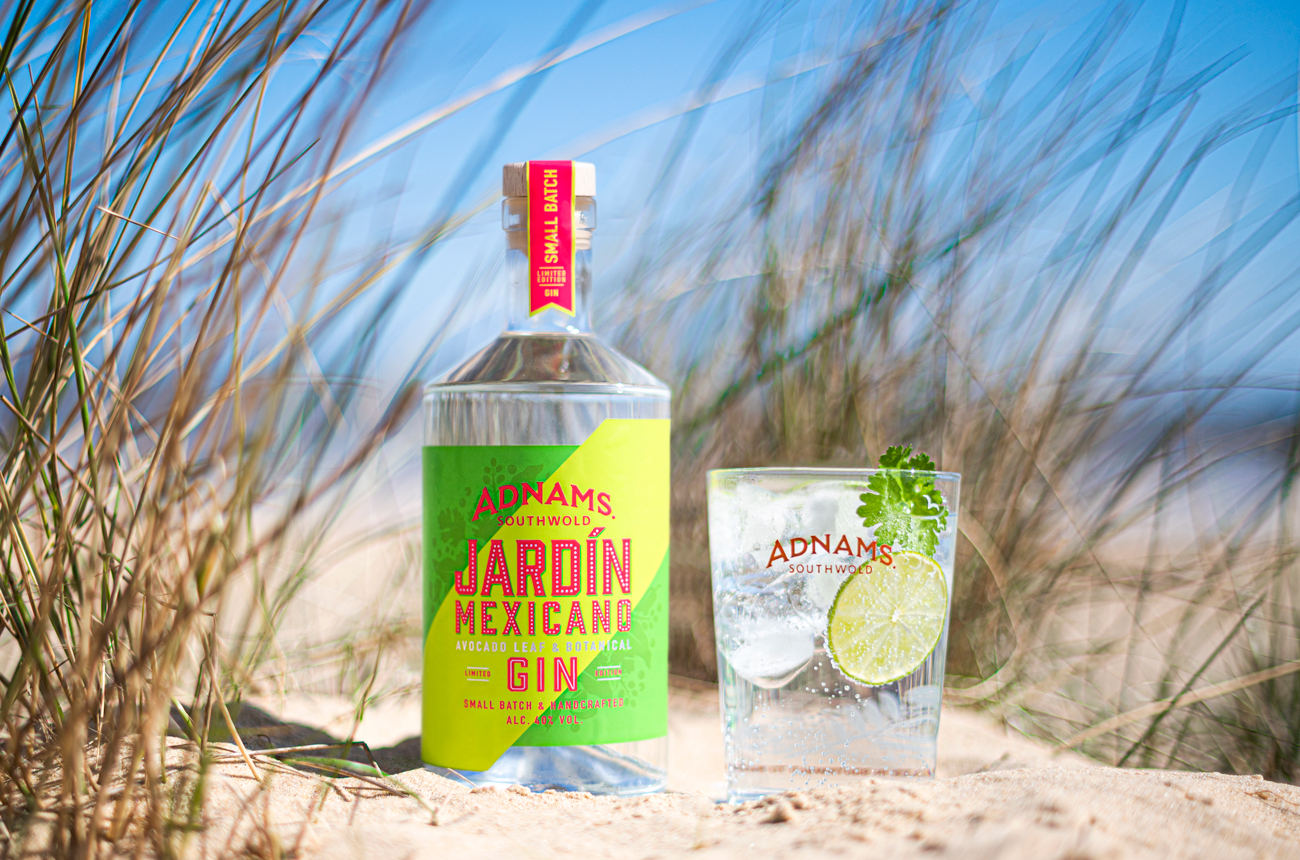 Bottle of Jardin Mexicano gin and a glass on a sandy beach