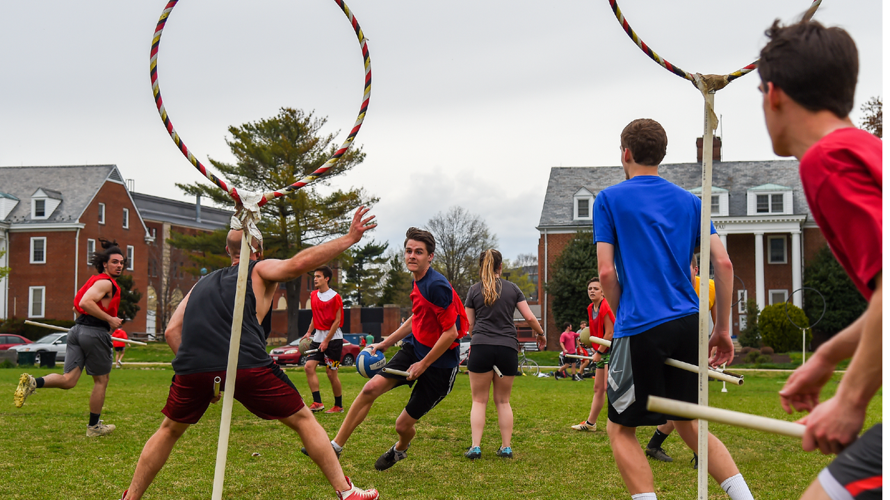 Student runs with ball towards a hoop on a playing field