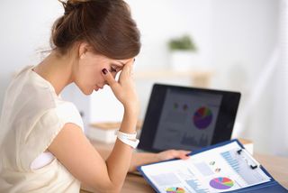 A woman sits in her office, looking stressed out.