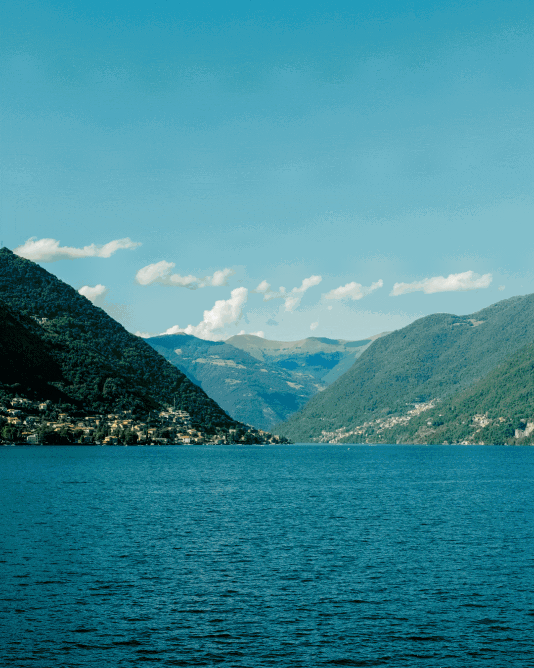 A rotating gif depicting statues and a sun-lit, lakeview landscape at the peak of summer.