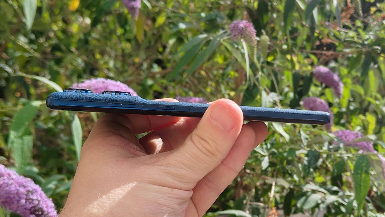 The Motorola Edge 60 in front of a flowery bush.