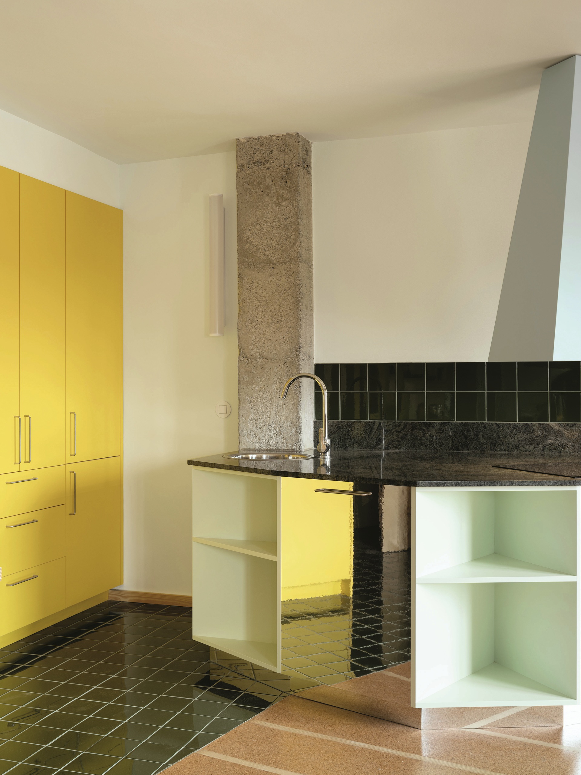 kitchen with angular island bench with mirrored cabinets, tiled floor, yellow cabinets, a black counter, and exposed concrete column
