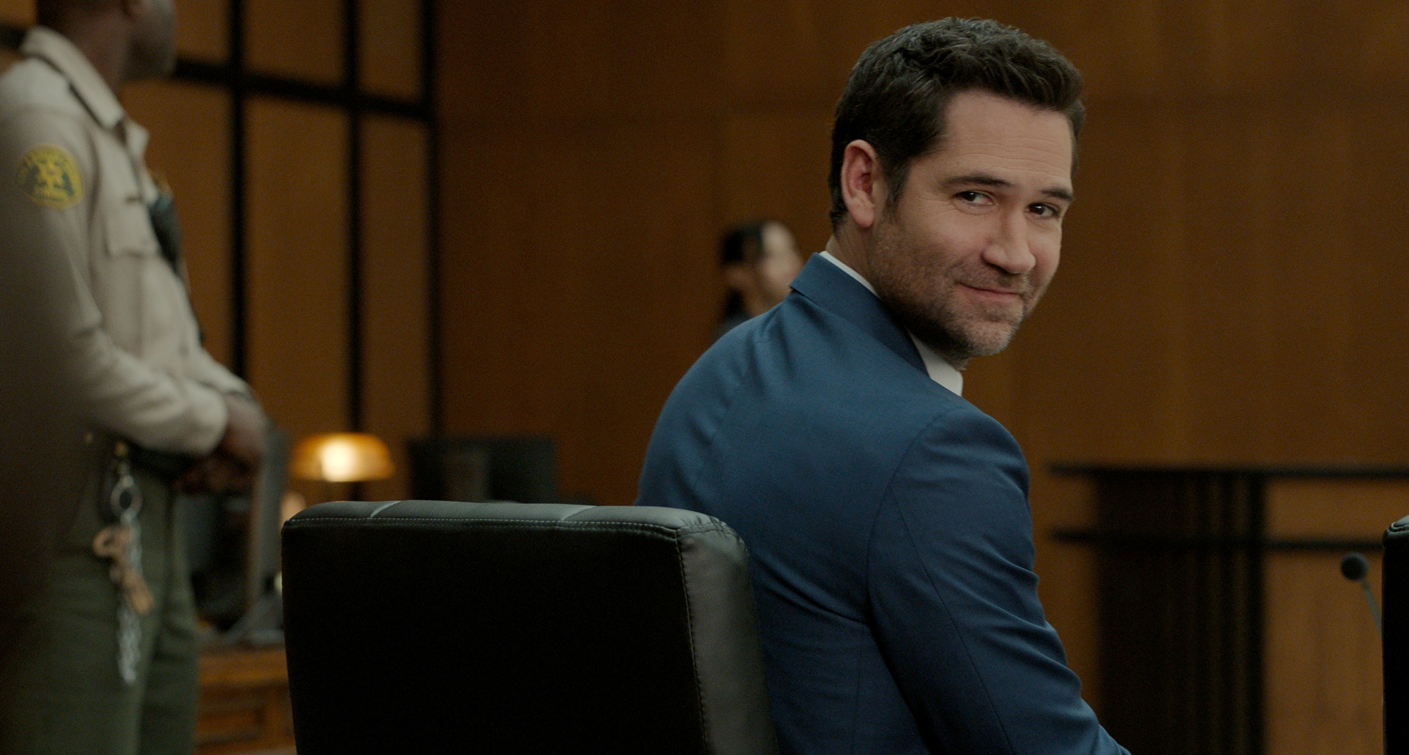 manuel garcia rulfo as mickey haller turning over his shoulder to look at the crowd in a court room in a still from the lincoln lawyer season 4