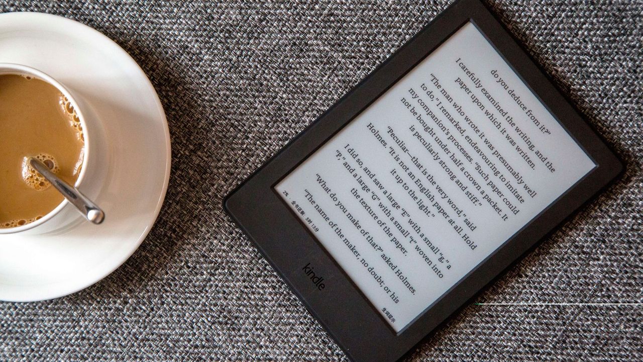 Kindle on a sofa next to a cup of coffee