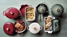 Red, white and pale green Le Creuset cookware on a pale green wooden background