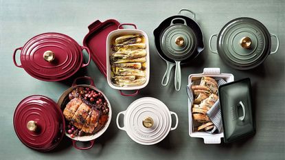 Red, white and pale green Le Creuset cookware on a pale green wooden background