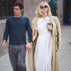 Elle Fanning walks in New York City wearing a Dôen dress with a matching trench coat and tortoiseshell sunglasses
