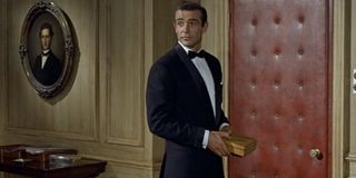 Dr No Sean Connery stands in a tuxedo holding a box
