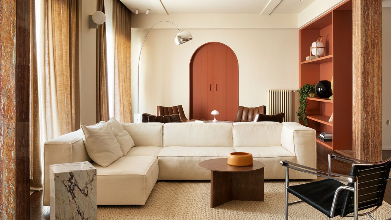 beige living room with timber elements, white sofa, marble plinth, red painted door and red cabinetry