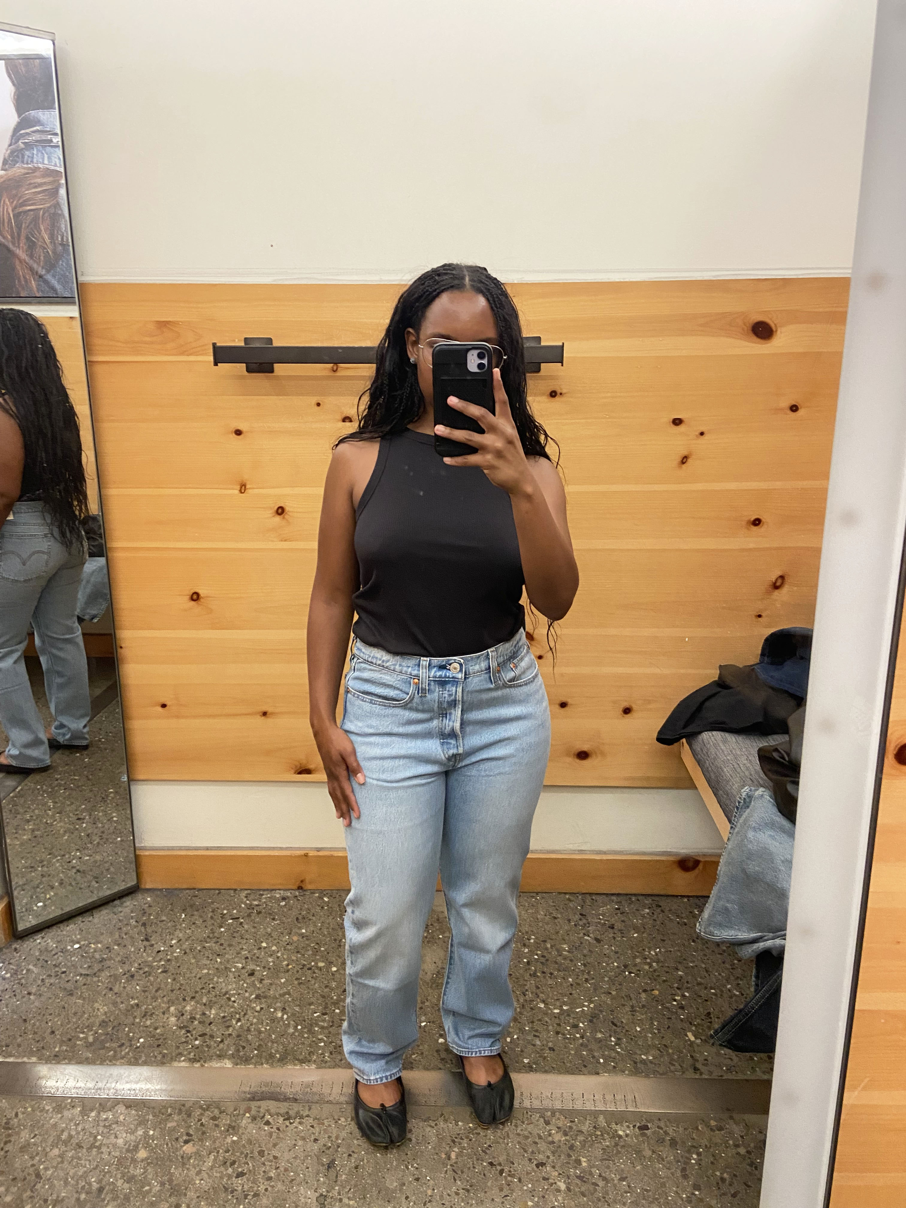 a woman wearing blue jeans and a black tank top