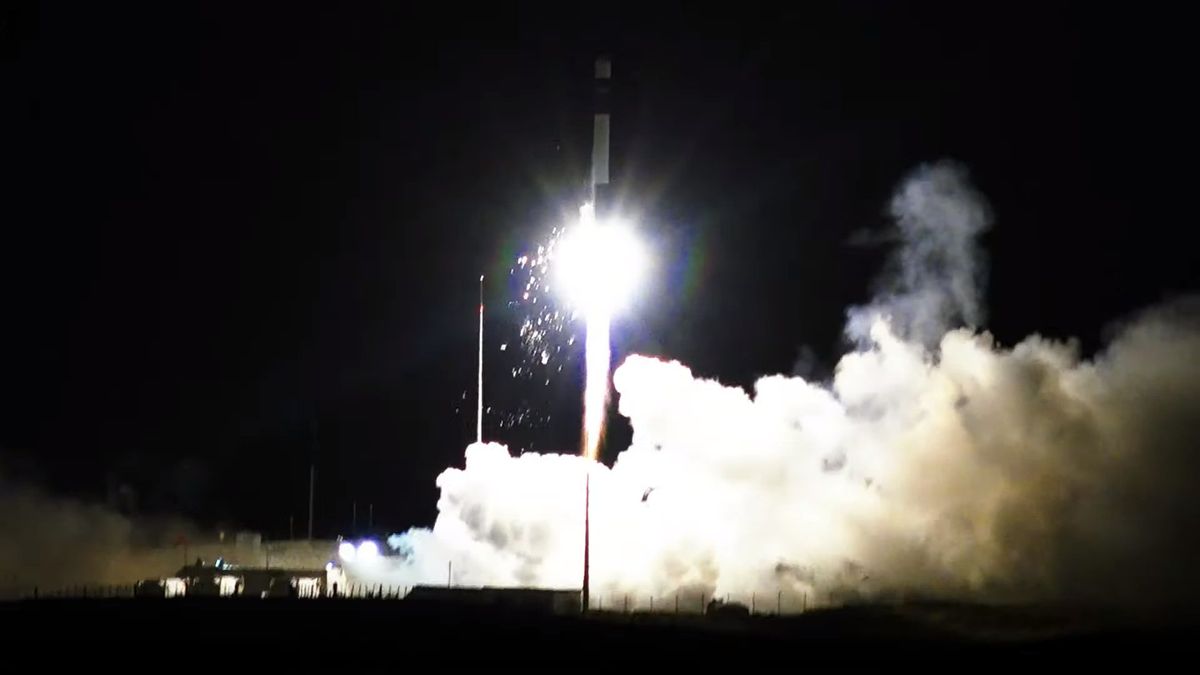 A white and black Rocket Lab Electron rocket launches into the nighttime sky with sparks spitting out from it on Feb. 18, 2024.