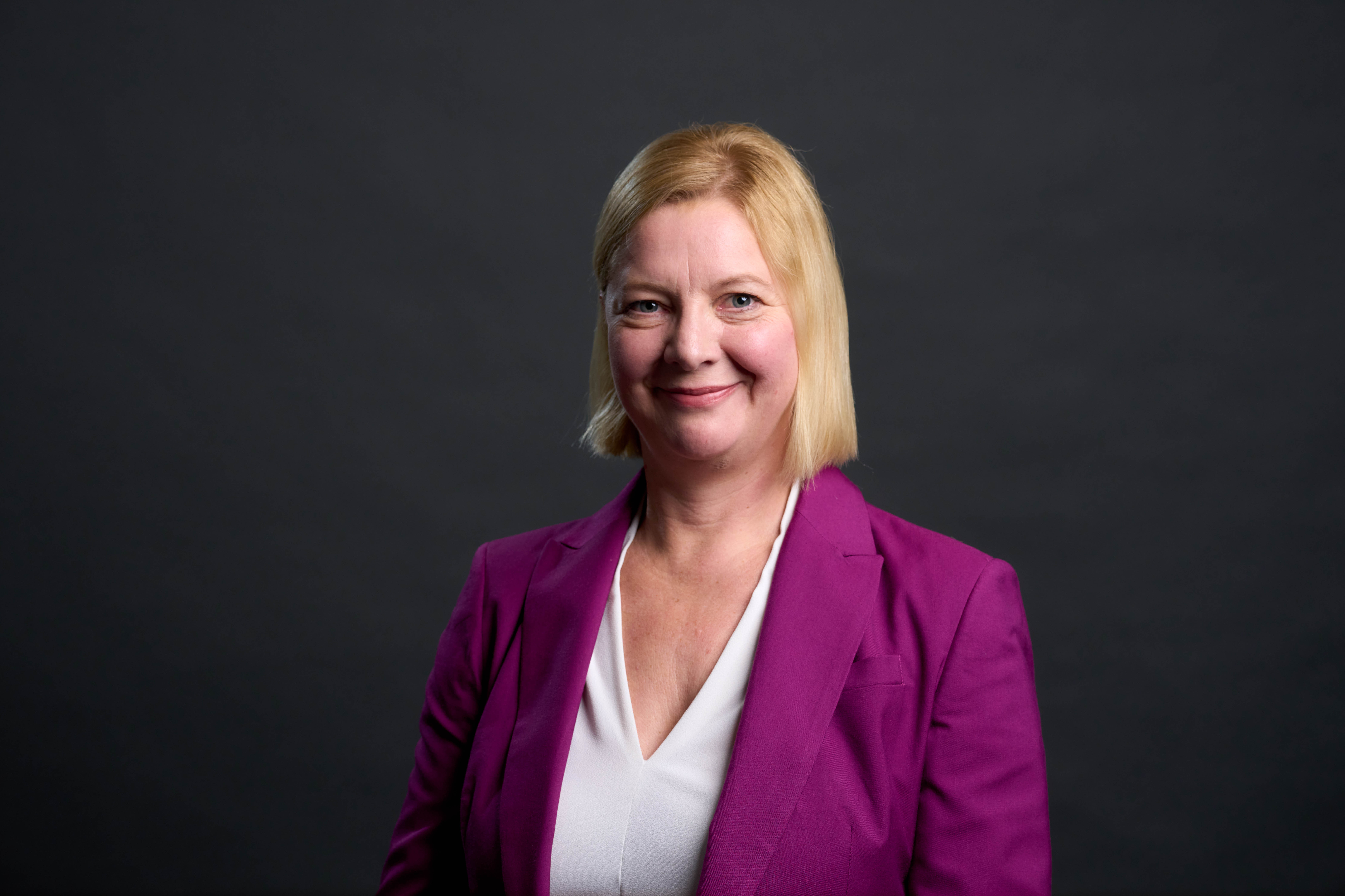 woman with short bobbed blonde hair wearing cerise jacket