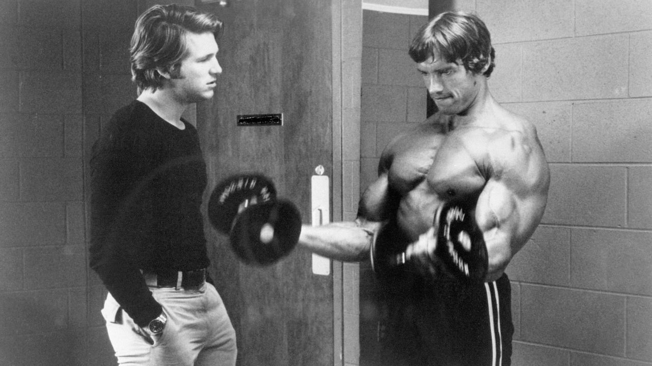 (Original Caption) April 1976- Jeff Bridges (L) and Arnold Schwarzenegger who is lifting weights in a movie still from &quot;Stay Hungry&quot;.