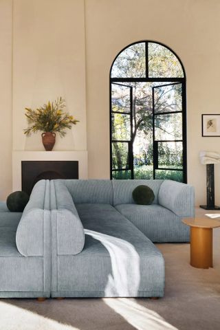 Image of a light blue corduroy sofa in a modern, all-beige living room.