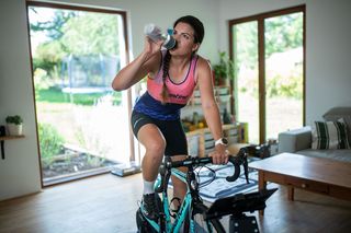 A cyclist rehydrating during an indoor training session