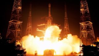 a large white rocket launches into a dark night sky