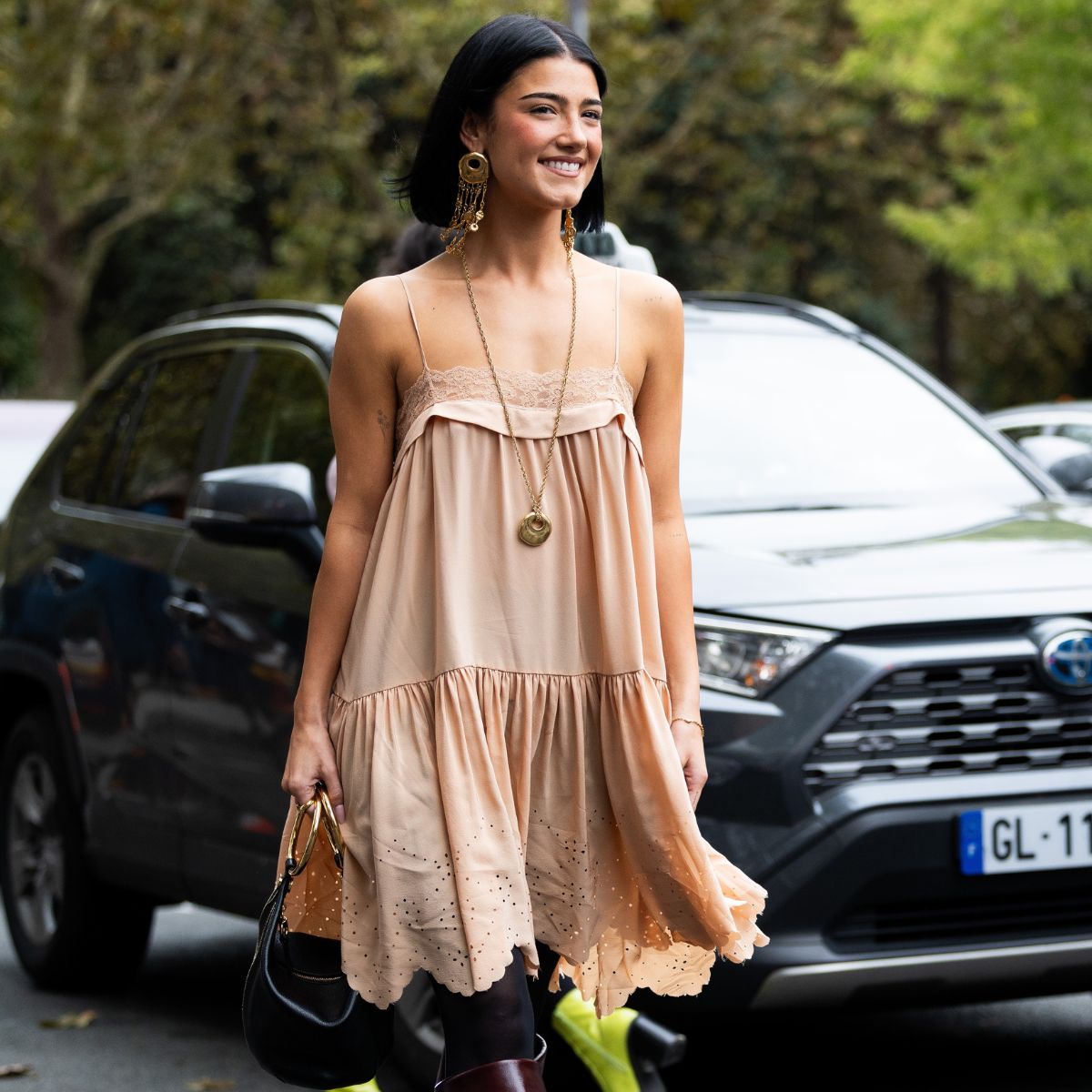 a street style star wearing a summer dress and boots