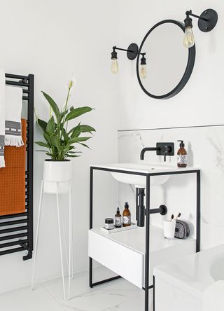 A striking monochrome bathroom with white walls and vanity sink with black bathroom taps and fittings