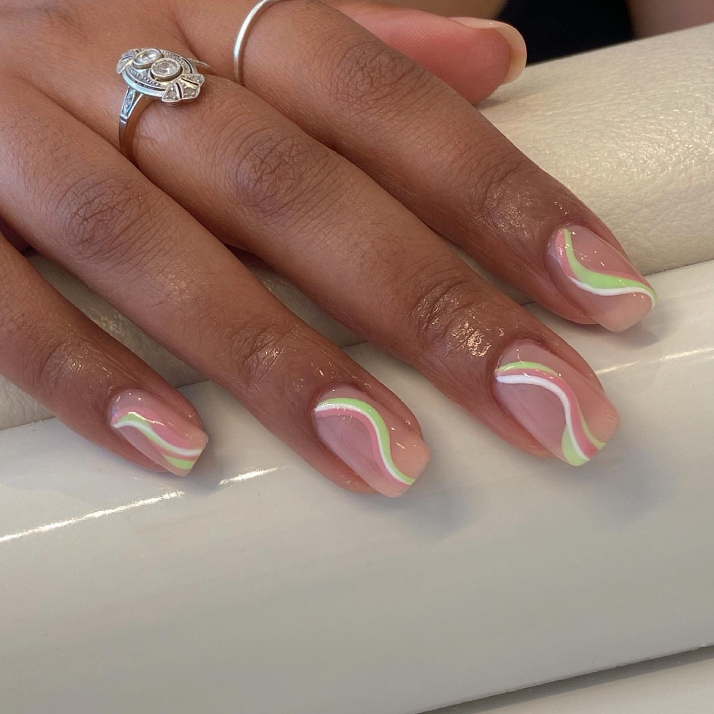 A pastel green and pink swirl nail design