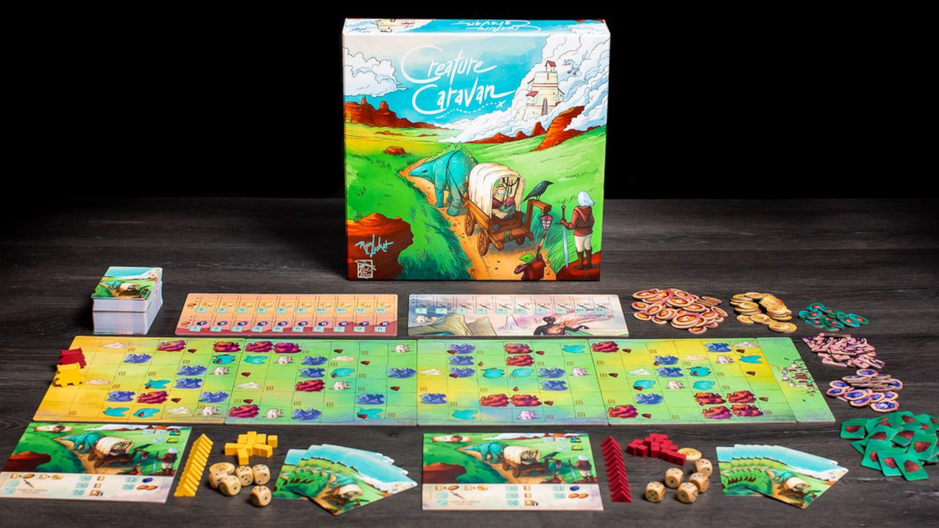 Creature Caravan box, board, cards, and components on a dark wooden table