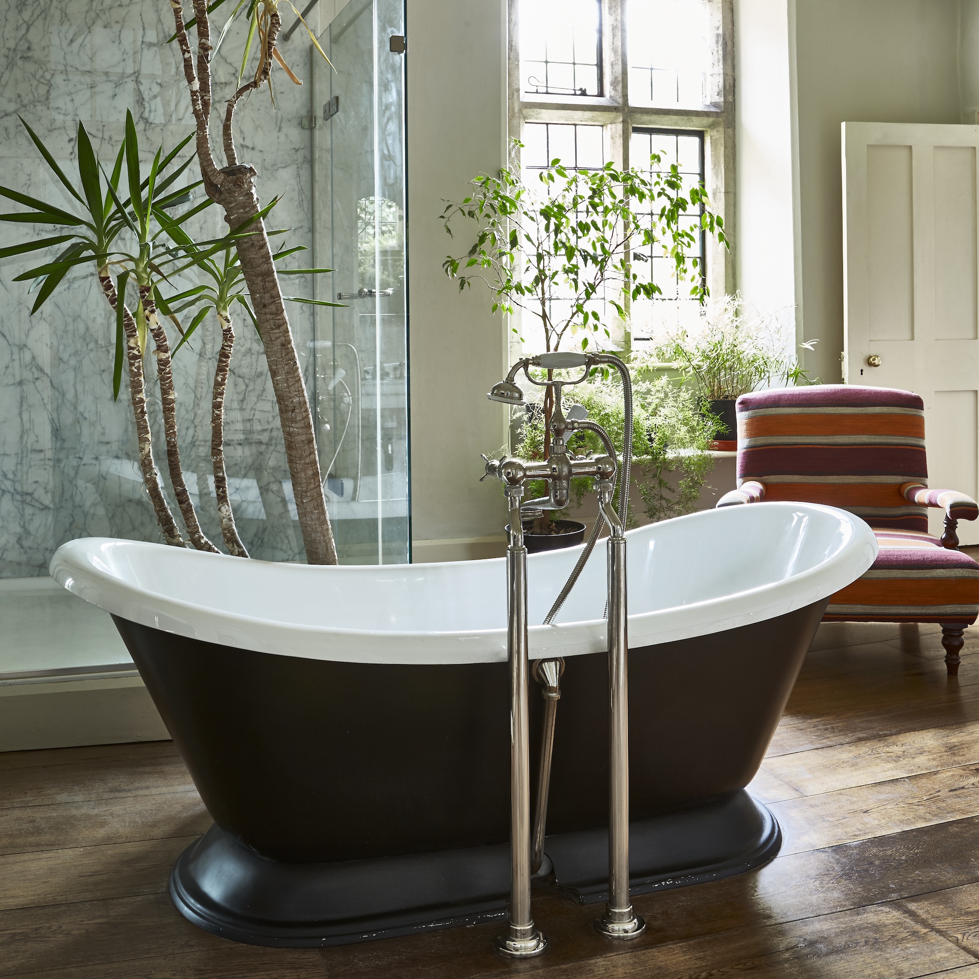 bathrom with large black freestanding slipper bath with floorstanding taps